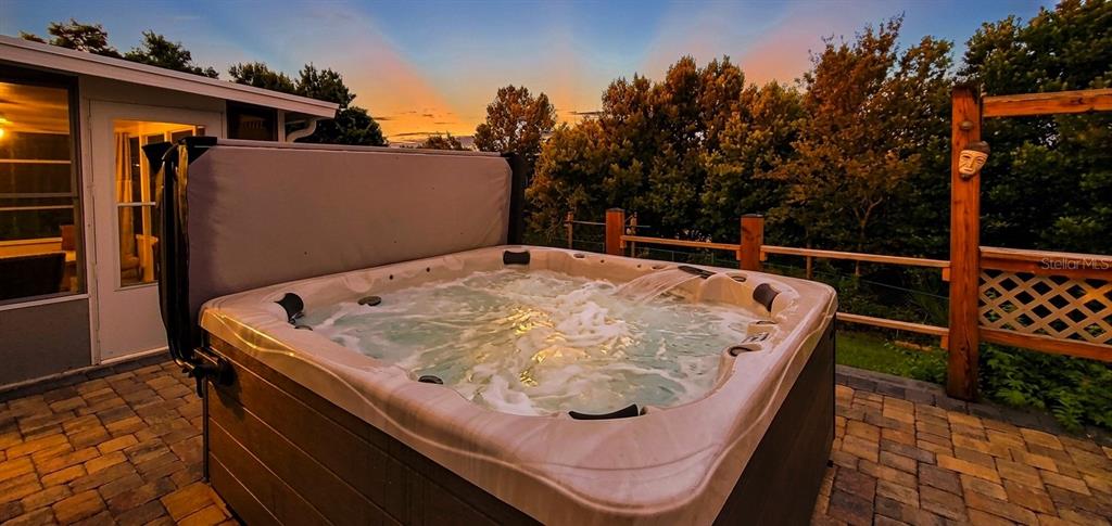 A hot tub sits on a paved patio at sunset next to a house exterior — 1371 S PRAIRIE CIRCLE, DELTONA, FL