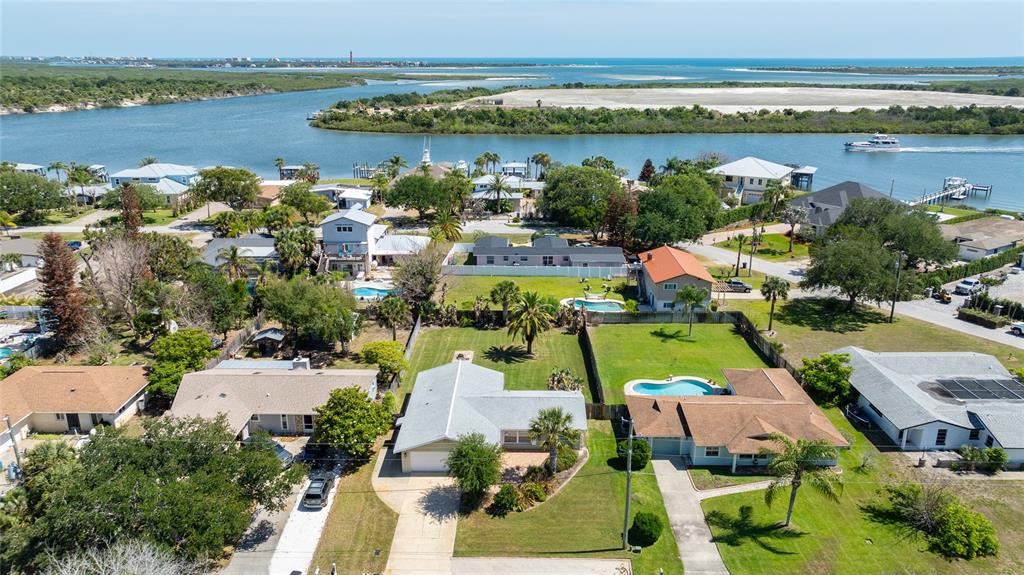 An aerial view shows several residential houses with swimming pools near a coastal waterway — 40 CUNNINGHAM DRIVE, NEW SMYRNA BEACH, FL