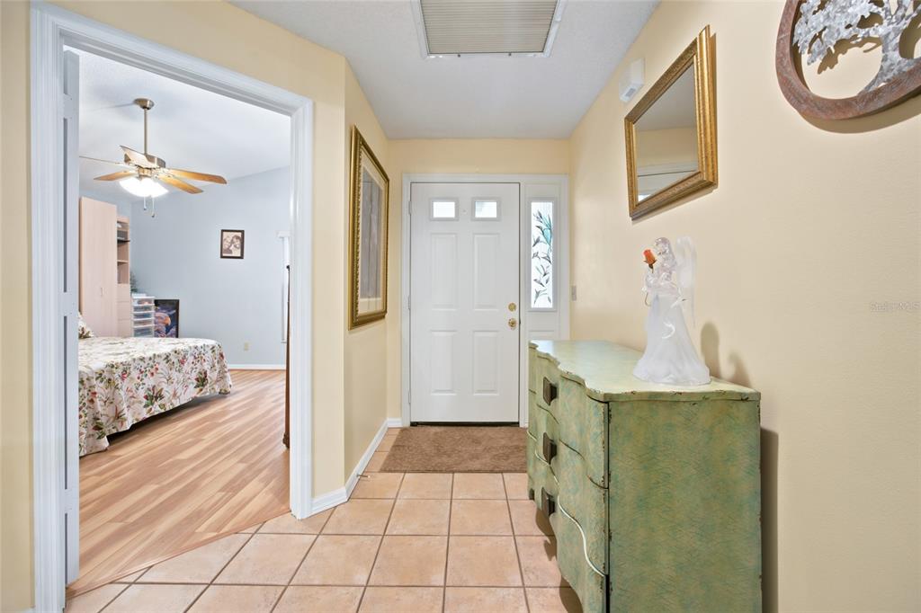 An entryway with tile flooring, a white front door, and a dresser leading into a bedroom — 9201 SW 91ST CIRCLE, OCALA, FL