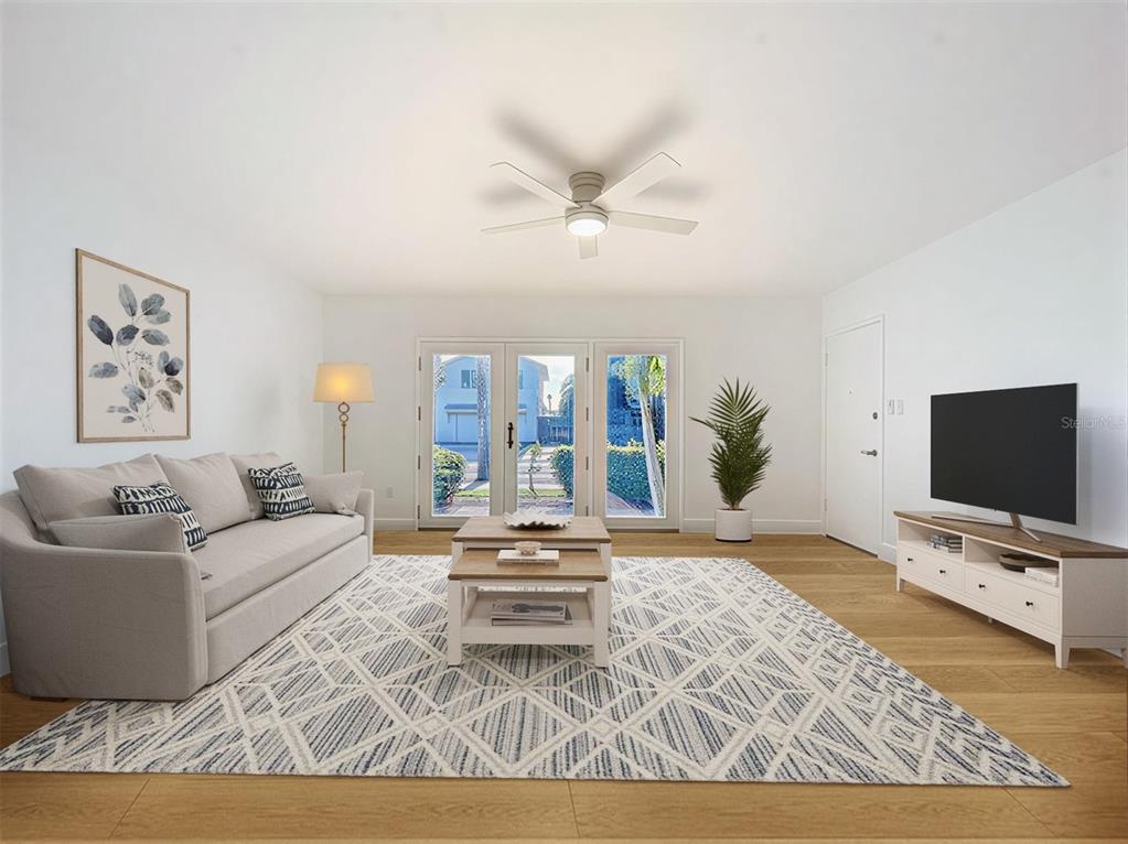 A living room features a light gray sofa, patterned area rug, and glass patio doors — 1800 PASS-A-GRILLE WAY UNIT 2, ST PETE BEACH, FL
