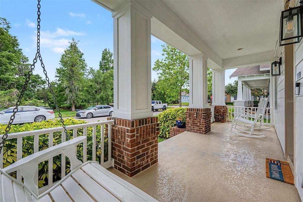 A covered front porch features a white swing, two rocking chairs, and brick-based columns — 3534 DIAZ STREET, NEW PORT RICHEY, FL