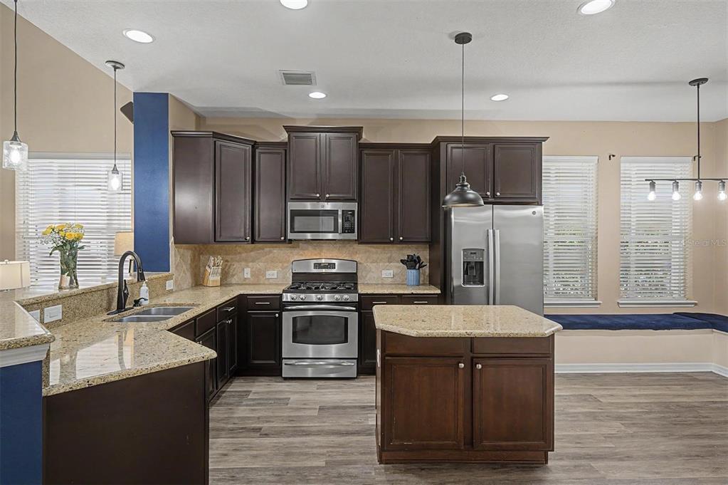 A kitchen features dark wood cabinets, granite countertops, stainless steel appliances, and a center island — 3534 DIAZ STREET, NEW PORT RICHEY, FL