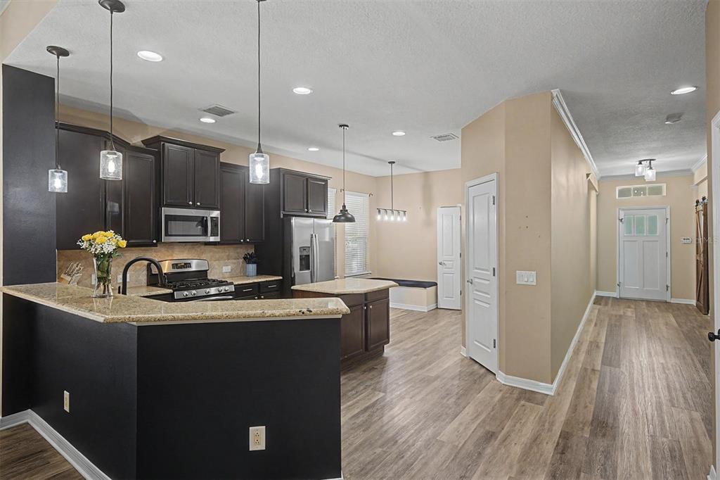A kitchen with dark cabinets, granite countertops, and an island opens to a dining area — 3534 DIAZ STREET, NEW PORT RICHEY, FL