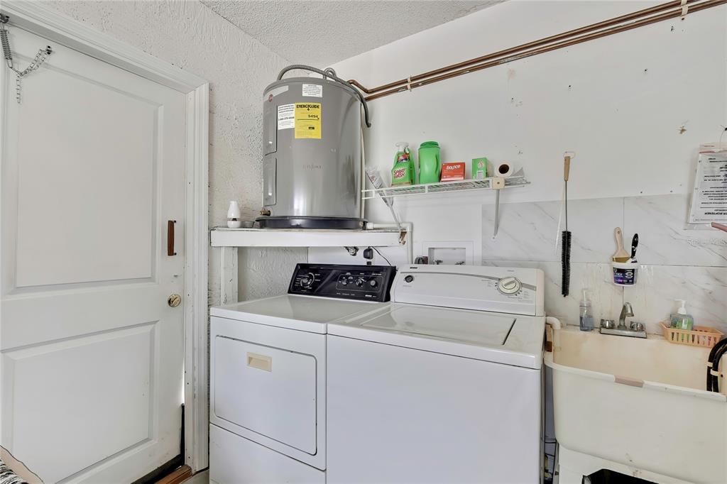 A laundry room features a water heater above a washer and dryer next to a sink — 7411 BALTUSROL DRIVE, NEW PORT RICHEY, FL