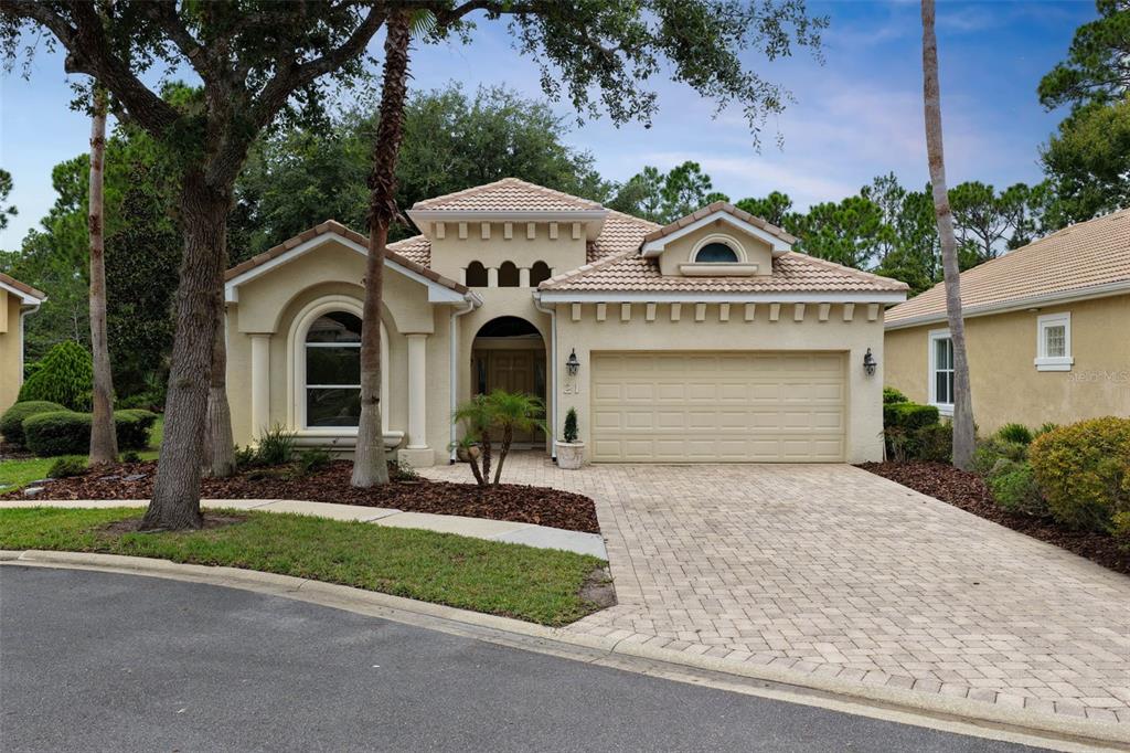 A single-story tan stucco house with a tiled roof, arched window, and paved driveway — 21 VILLAGE VIEW DRIVE, PALM COAST, FL