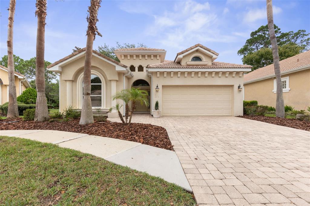 A single-story house with a beige stucco exterior, a tiled roof, and a paved driveway — 21 VILLAGE VIEW DRIVE, PALM COAST, FL