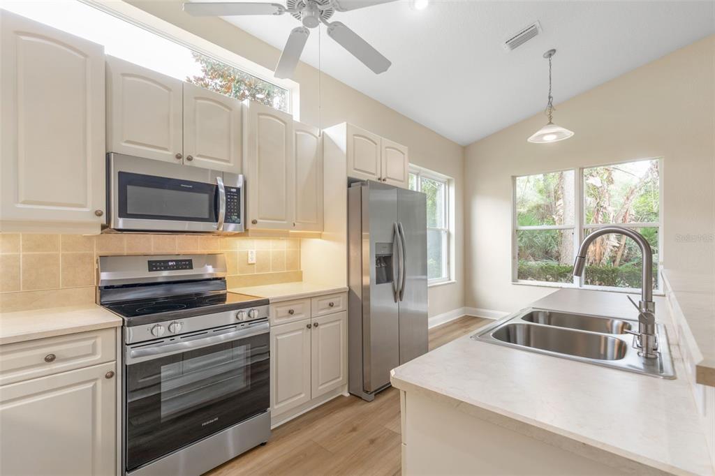 A kitchen with white cabinets, stainless steel appliances, a double sink, and light wood flooring — 21 VILLAGE VIEW DRIVE, PALM COAST, FL