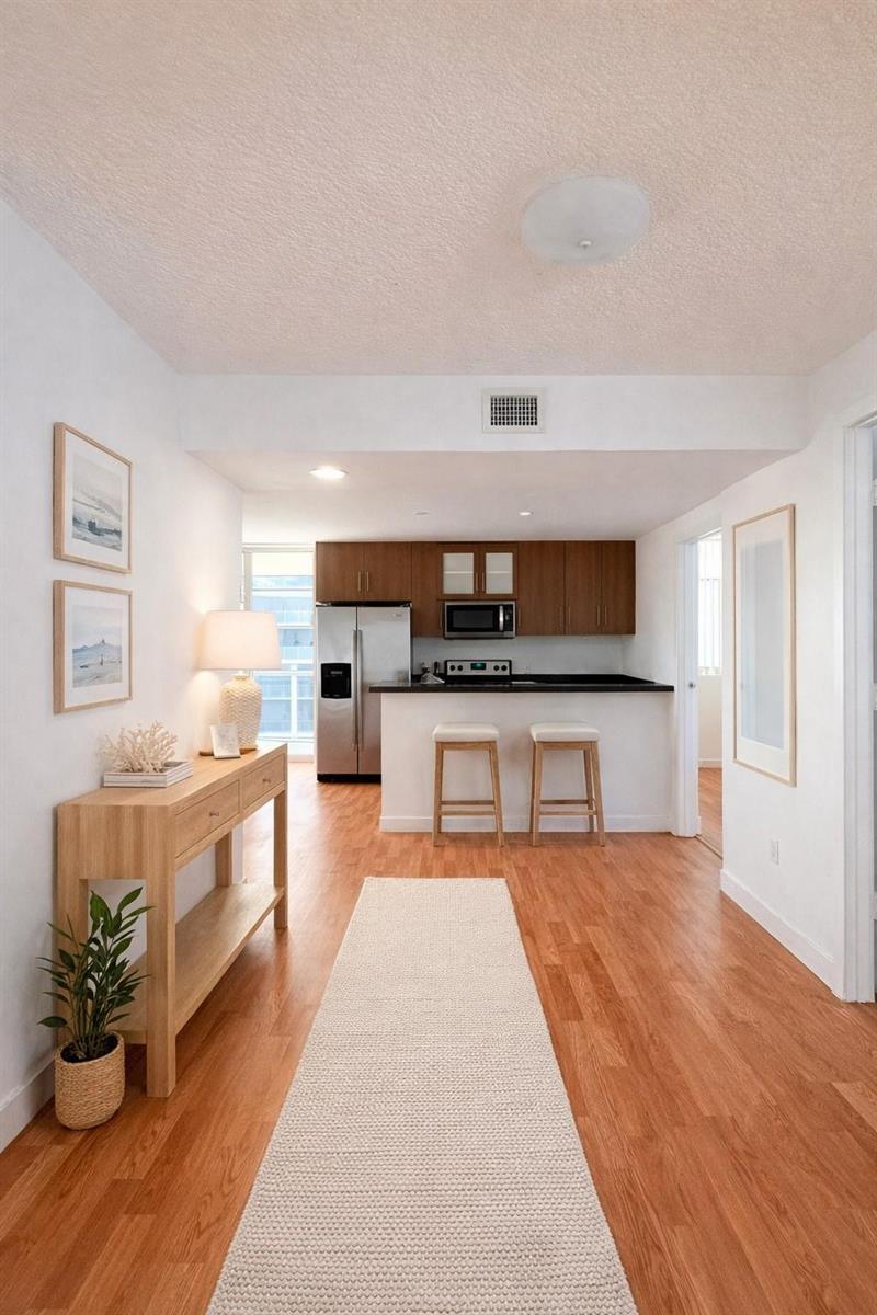 A hallway with a wooden console table leads to a kitchen featuring wood cabinetry — 601 NE 23rd Street # 902, Miami FL 33137, MIAMI, FL