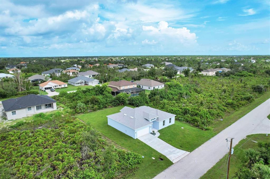 An aerial view shows a single-story house with a gray roof surrounded by undeveloped land — 9245 ZORN STREET, PORT CHARLOTTE, FL