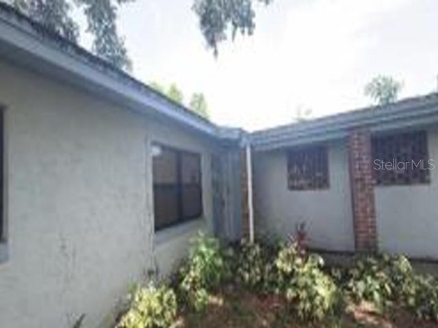 A view of a house exterior with light-colored walls, a brick accent, and landscaping — 1150 MORSE AVENUE, TITUSVILLE, FL