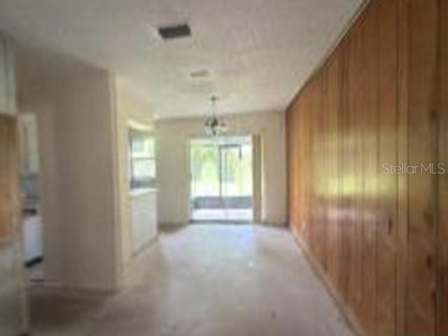 An interior view of a room featuring wood-paneled walls, a light-colored floor, and a sliding door — 1150 MORSE AVENUE, TITUSVILLE, FL