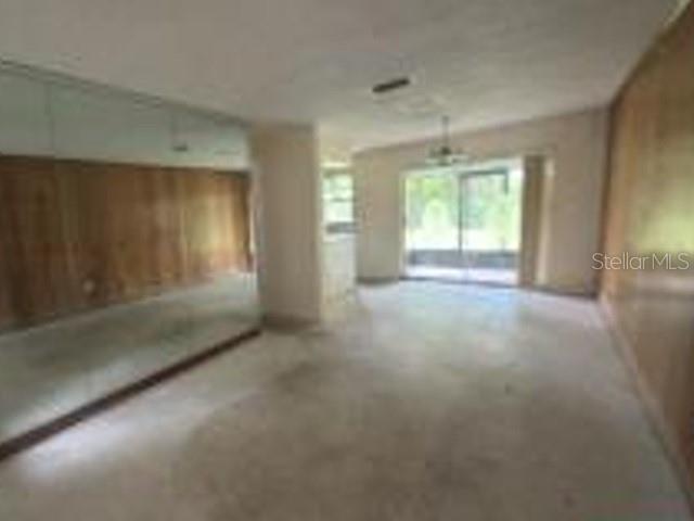 An interior room features wood-paneled walls, a large wall mirror, and a sliding glass door — 1150 MORSE AVENUE, TITUSVILLE, FL