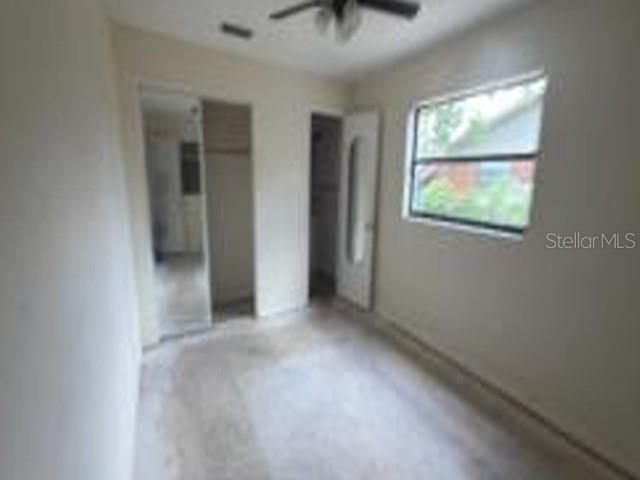 An empty bedroom with beige walls, a ceiling fan, a closet, and a window — 1150 MORSE AVENUE, TITUSVILLE, FL