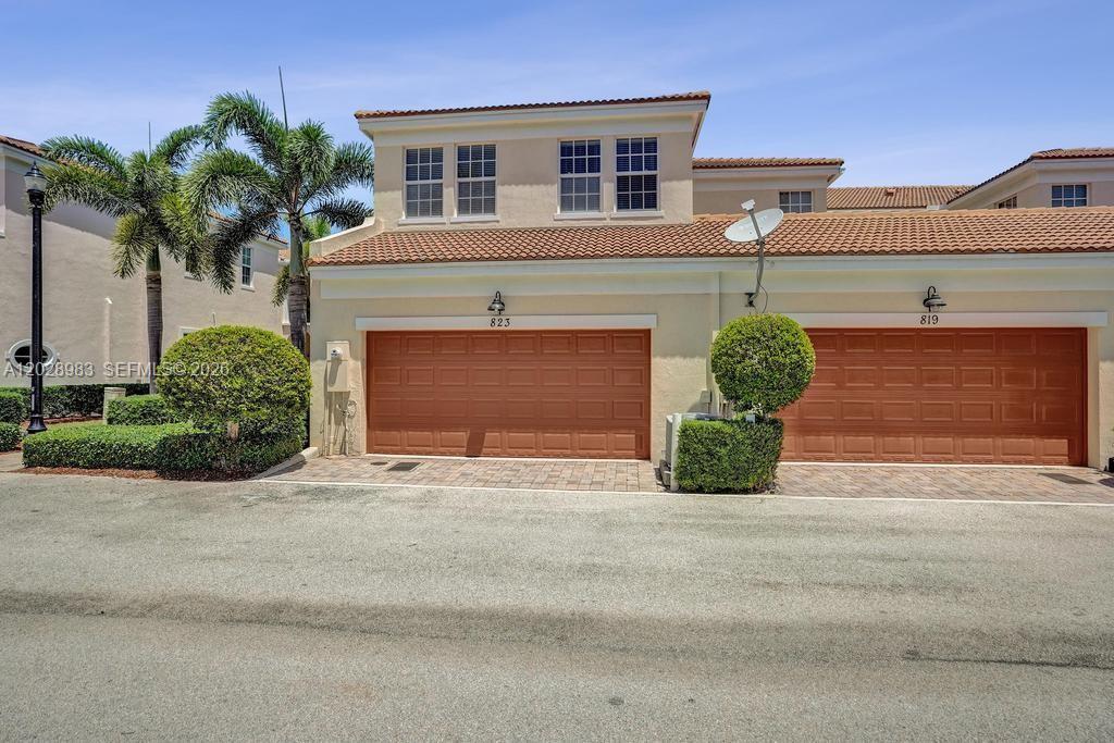 The exterior of a two-story townhouse features two brown garage doors and palm trees — 823 NW 82nd Ln, Boca Raton FL 33487, BOCA RATON, FL