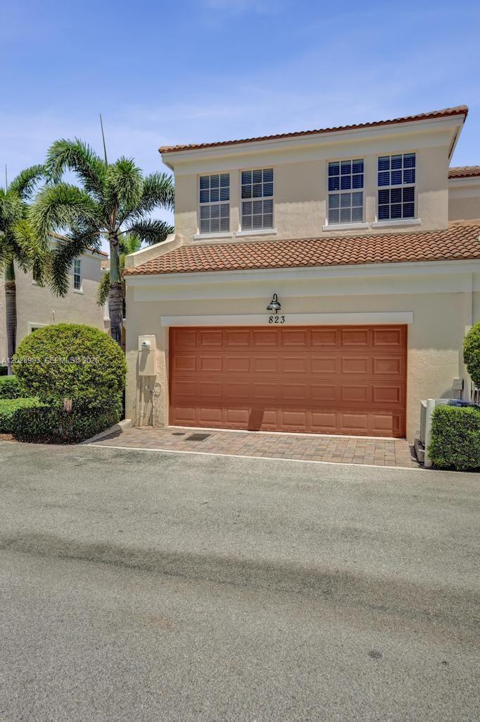 A two-story residential building features a tan stucco exterior, a brown garage door, and landscaping — 823 NW 82nd Ln, Boca Raton FL 33487, BOCA RATON, FL