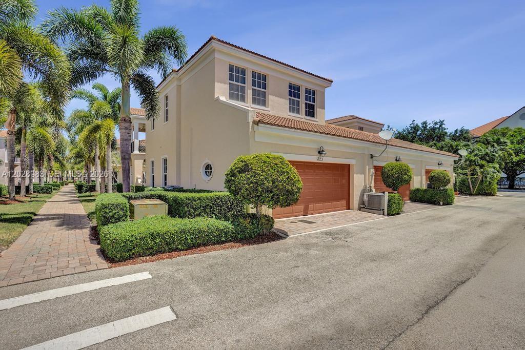 A two-story beige townhouse with a two-car garage and palm trees in the foreground — 823 NW 82nd Ln, Boca Raton FL 33487, BOCA RATON, FL