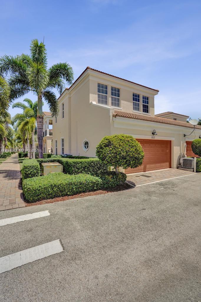A two-story beige townhouse features a brown garage door and manicured hedges — 823 NW 82nd Ln, Boca Raton FL 33487, BOCA RATON, FL