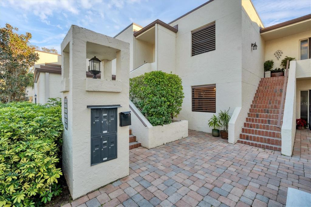 An exterior view of a multi-unit building with a brick staircase and a mailbox kiosk — 5032 MARSHFIELD ROAD UNIT 19, SARASOTA, FL