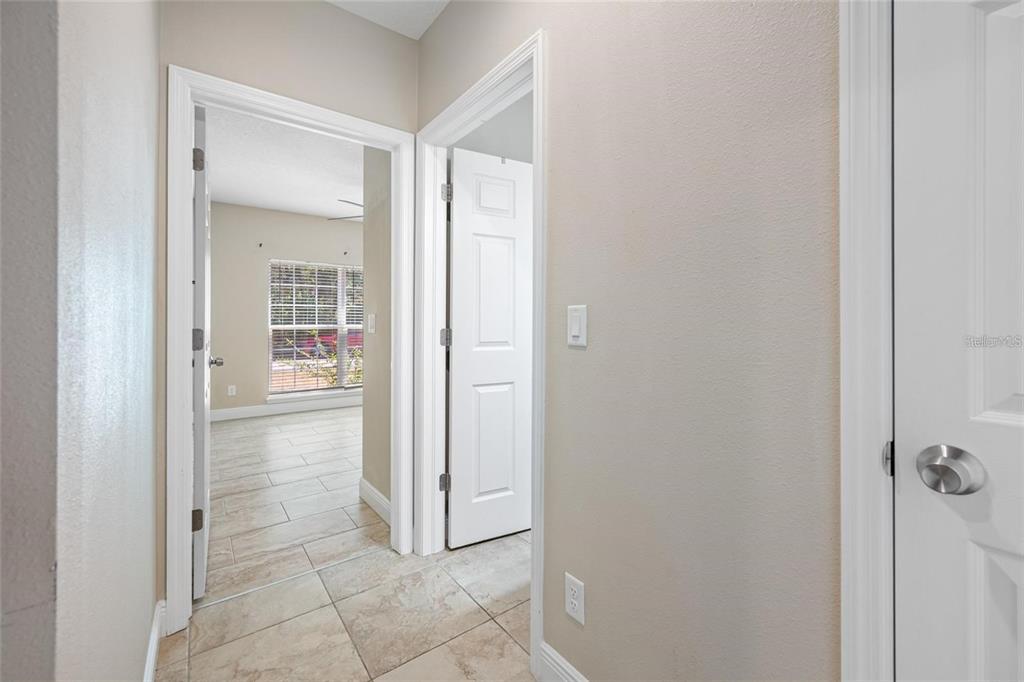 A hallway with tiled floors leads to a bedroom and a closed white door — 230 CLAYTON STREET, BRANDON, FL