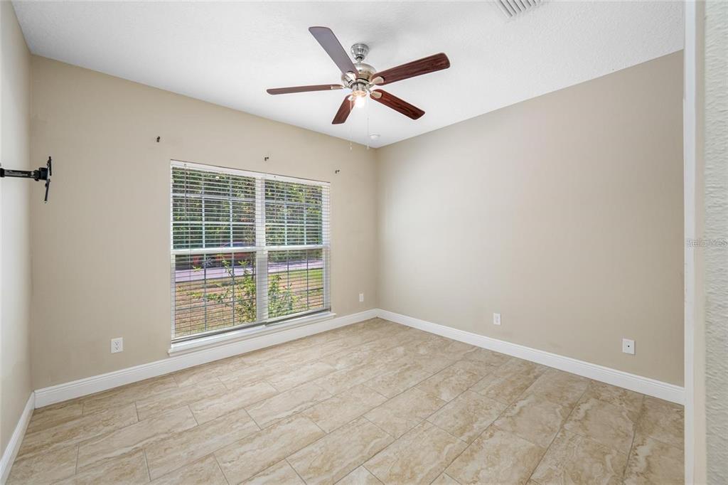 An empty room features beige walls, tile flooring, a ceiling fan, and a large window — 230 CLAYTON STREET, BRANDON, FL