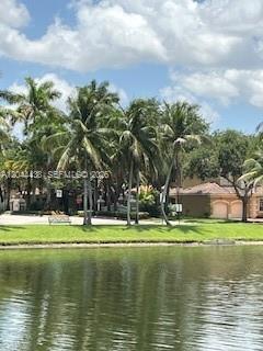 A view of a grassy waterfront area with palm trees and houses in the background — HOLLYWOOD, FL