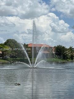A large water fountain sprays into a lake in front of a residential building — HOLLYWOOD, FL