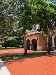 A two-story tan stucco house with a red brick driveway and a two-car garage — HOLLYWOOD, FL