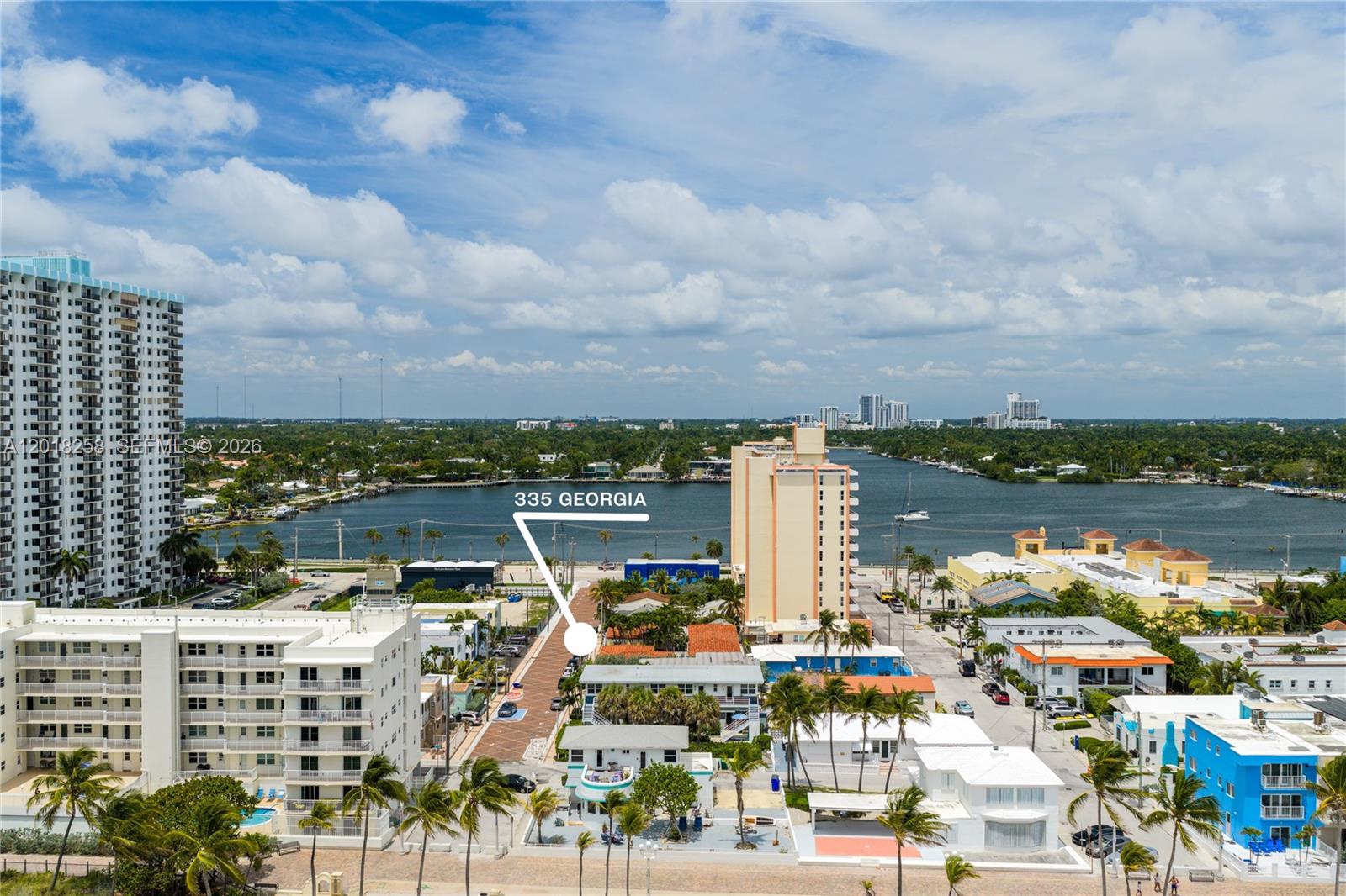 An aerial view shows a coastal neighborhood with low-rise buildings, palm trees, and a waterway — 335 Georgia St, Hollywood FL 33019, HOLLYWOOD, FL