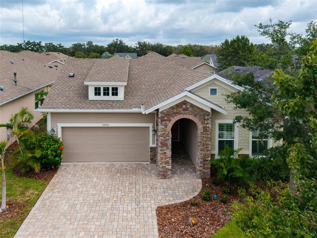 An exterior view of a single-story house with a stone-accented entryway and paved driveway — 14008 SWALLOW HILL DRIVE, LITHIA, FL