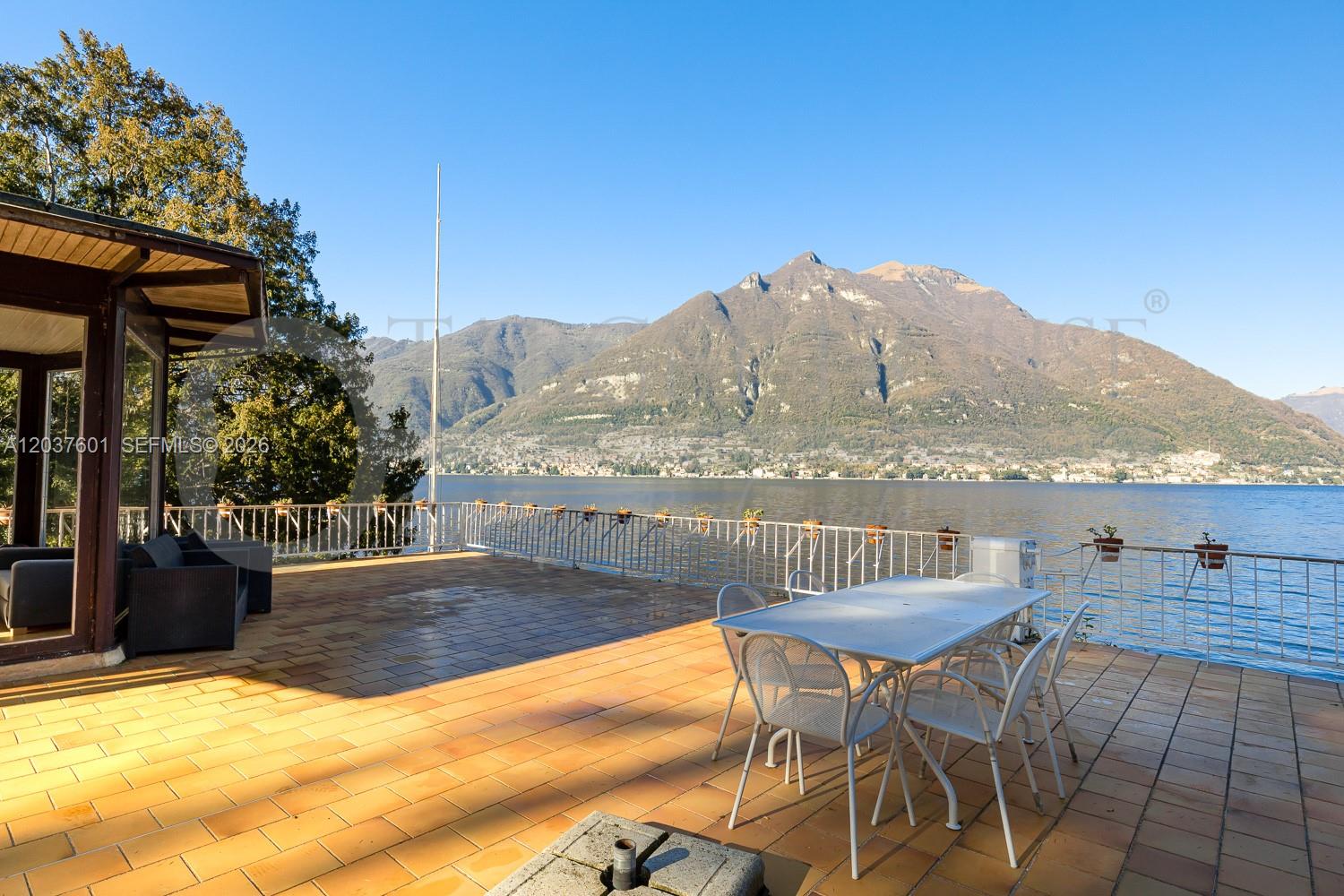 A tiled outdoor terrace overlooks a lake with mountains in the background — lago di Como lake front, VA 22100, VA