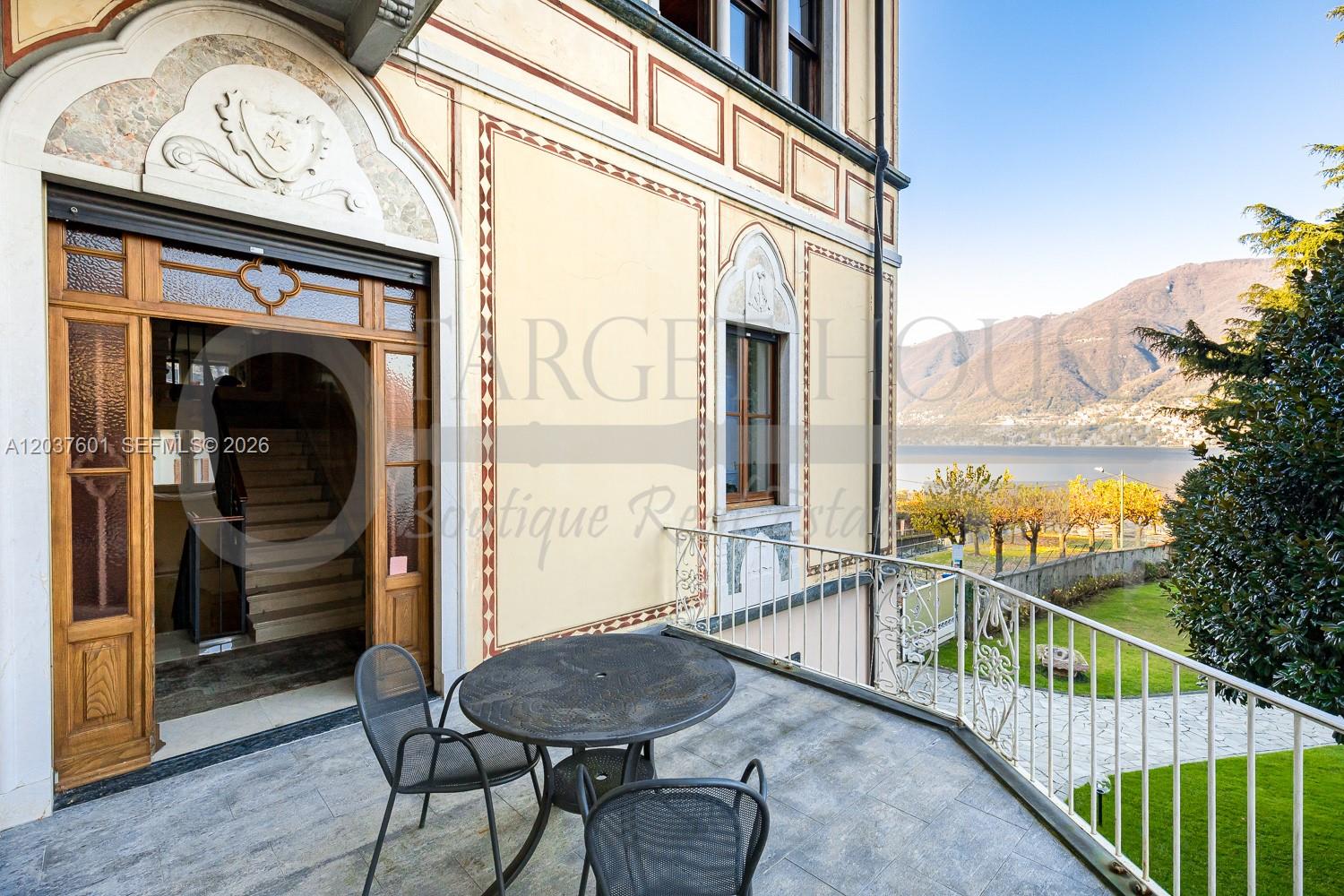 A stone balcony with a table and chairs overlooks a lake and mountains — lago di Como lake front, VA 22100, VA