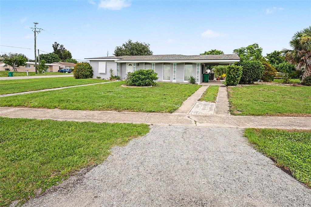 A single-story house with a gravel driveway, a carport, and a front lawn — 21422 MALLORY AVENUE, PORT CHARLOTTE, FL