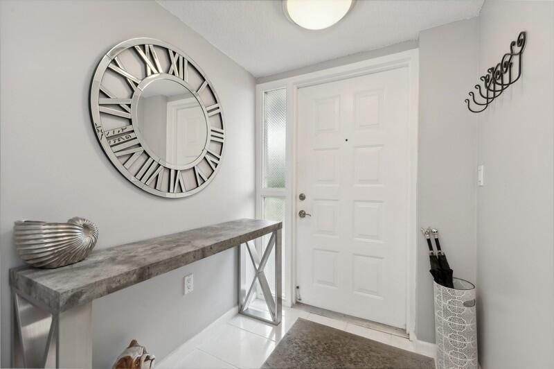 An entryway features a console table, a large round wall clock, and a white door — 6530 Boca Del Mar Drive # 337, Boca Raton FL 33433, BOCA RATON, FL