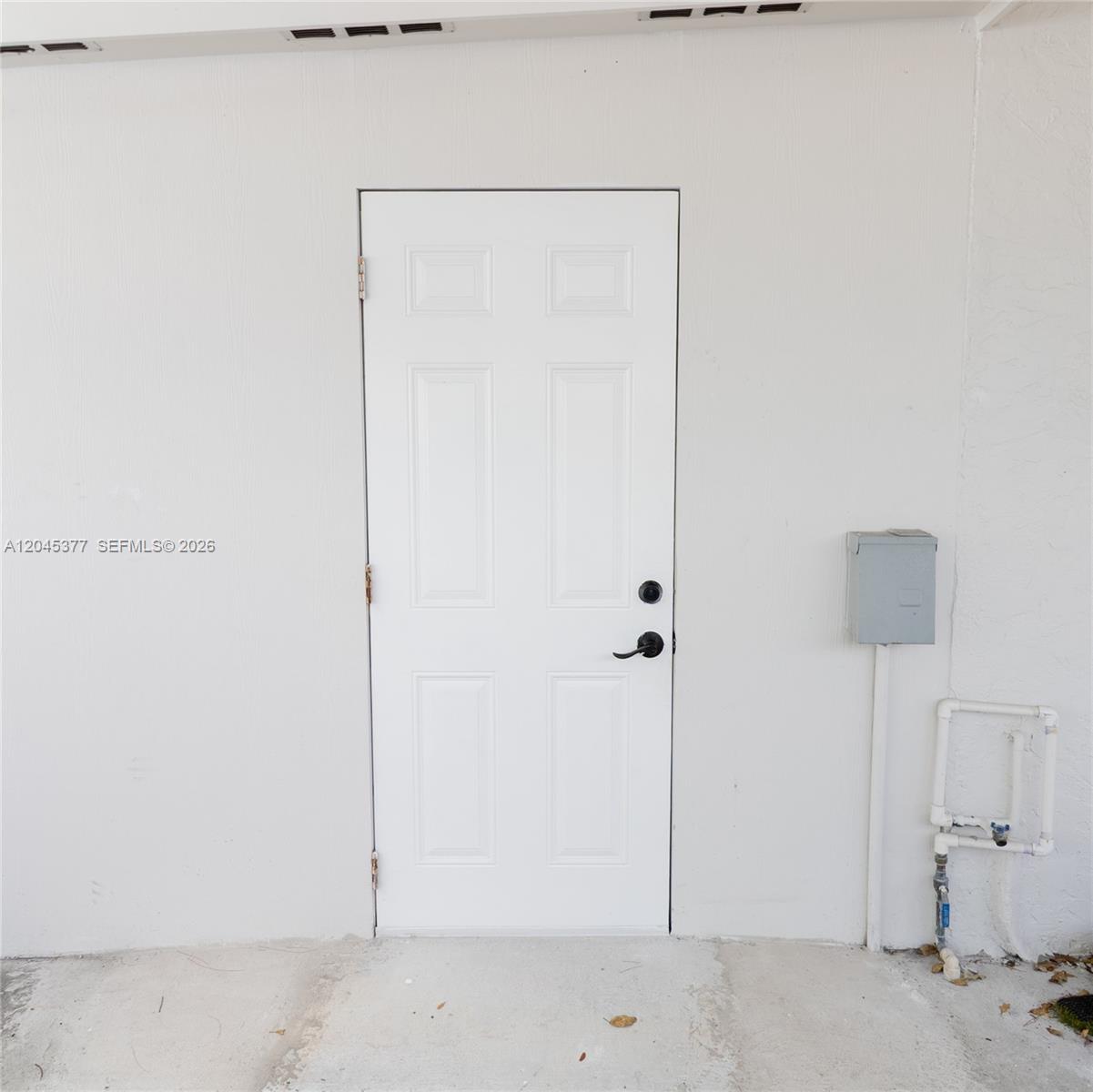 A white exterior door is set into a plain wall with an adjacent electrical box — 5803 Buchanan St, Hollywood FL 33021, HOLLYWOOD, FL