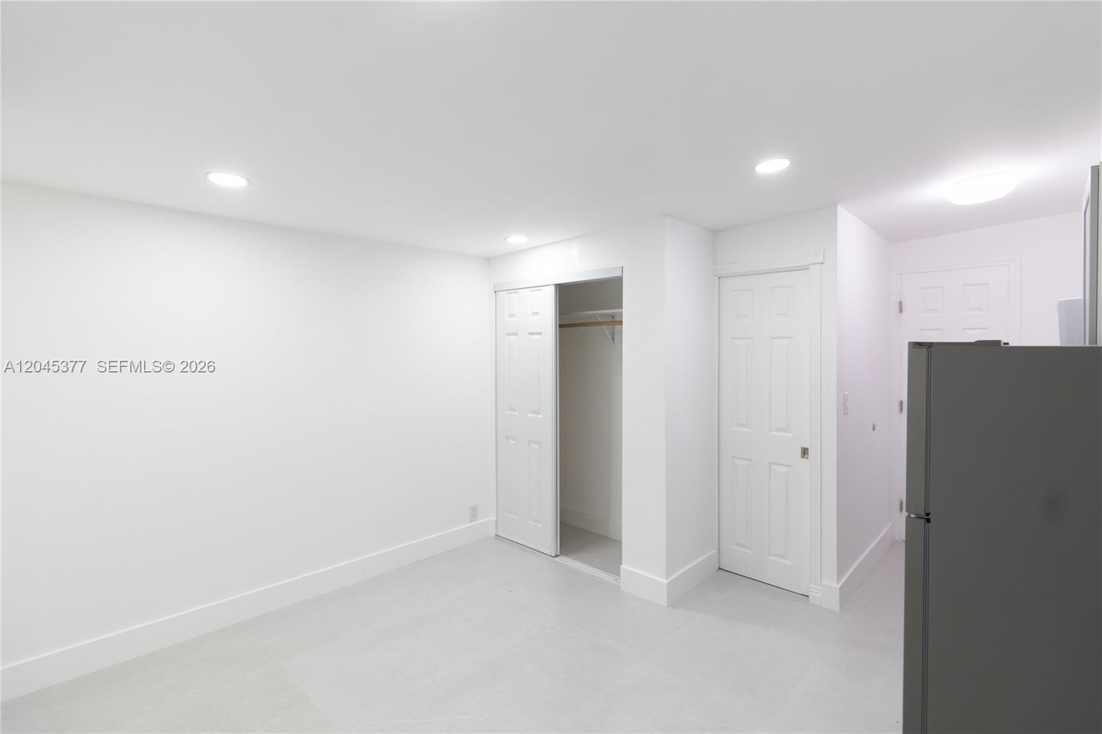 A minimalist room features white walls, light tile flooring, recessed lighting, and two white doors — 5803 Buchanan St, Hollywood FL 33021, HOLLYWOOD, FL