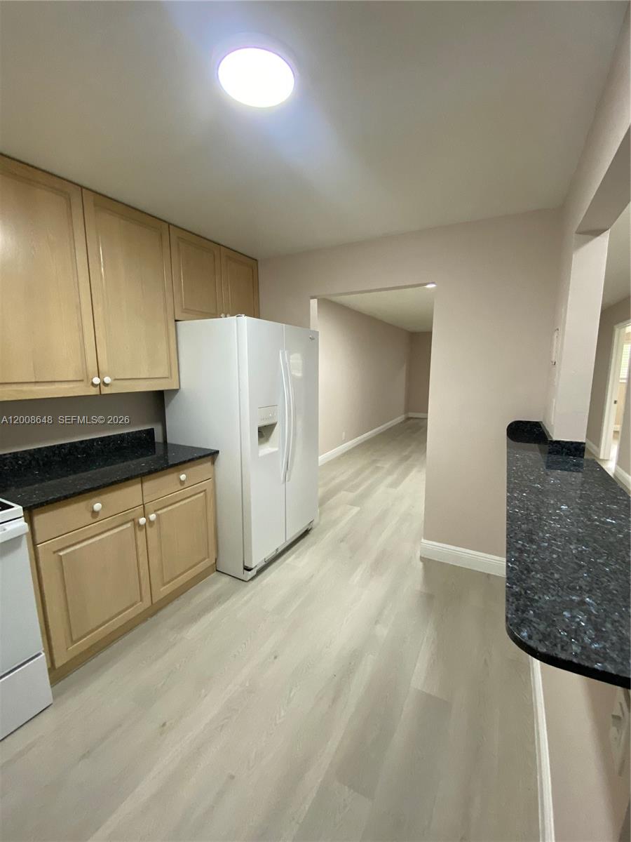 A kitchen features light wood cabinets, dark granite countertops, and a white refrigerator — 605 S State Road 7 # 3F, Margate FL 33068, MARGATE, FL