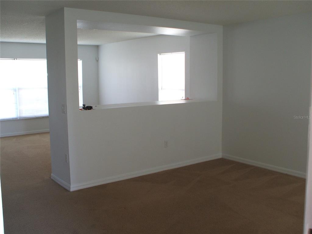 A carpeted room features a large rectangular opening in a white partition wall — 2872 PAYNES PRAIRIE CIRCLE, KISSIMMEE, FL