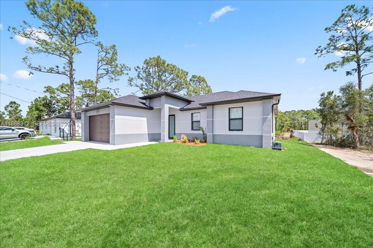 A single-story house with a gray and white exterior, a garage, and a front lawn — 727 Drury Ave, Lehigh Acres FL 33974, LEHIGH ACRES, FL