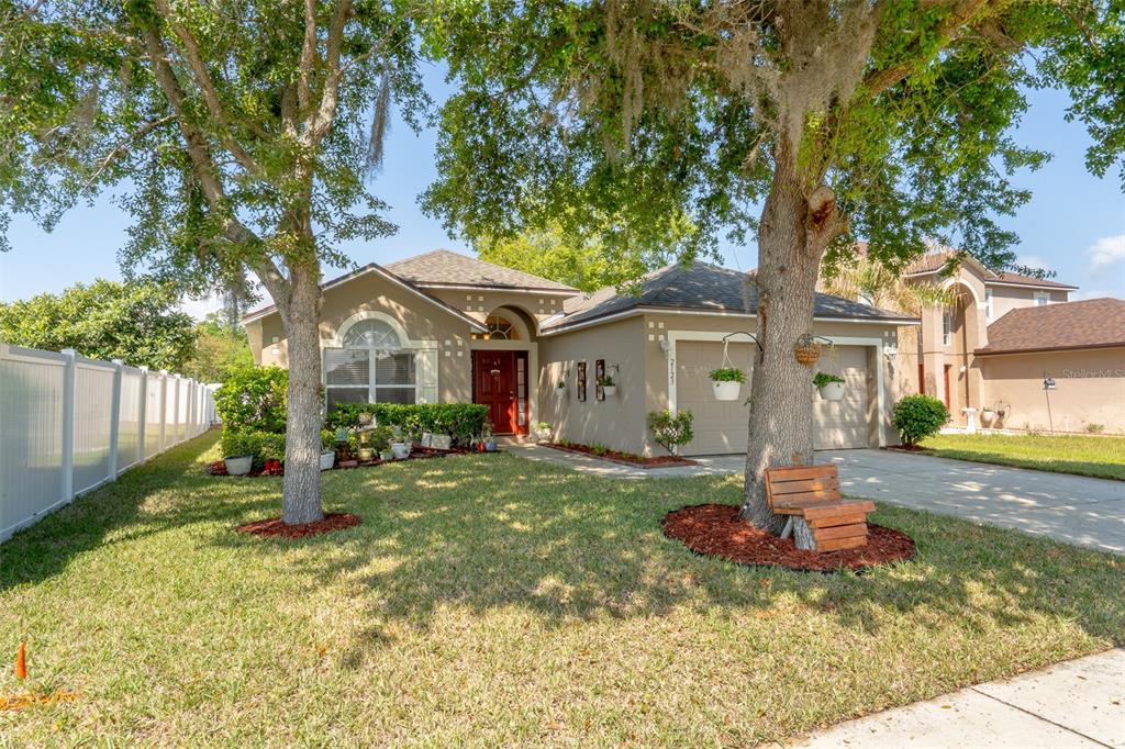A single-story tan house with a red front door and a two-car garage — 2123 ANOKA WAY, LEESBURG, FL