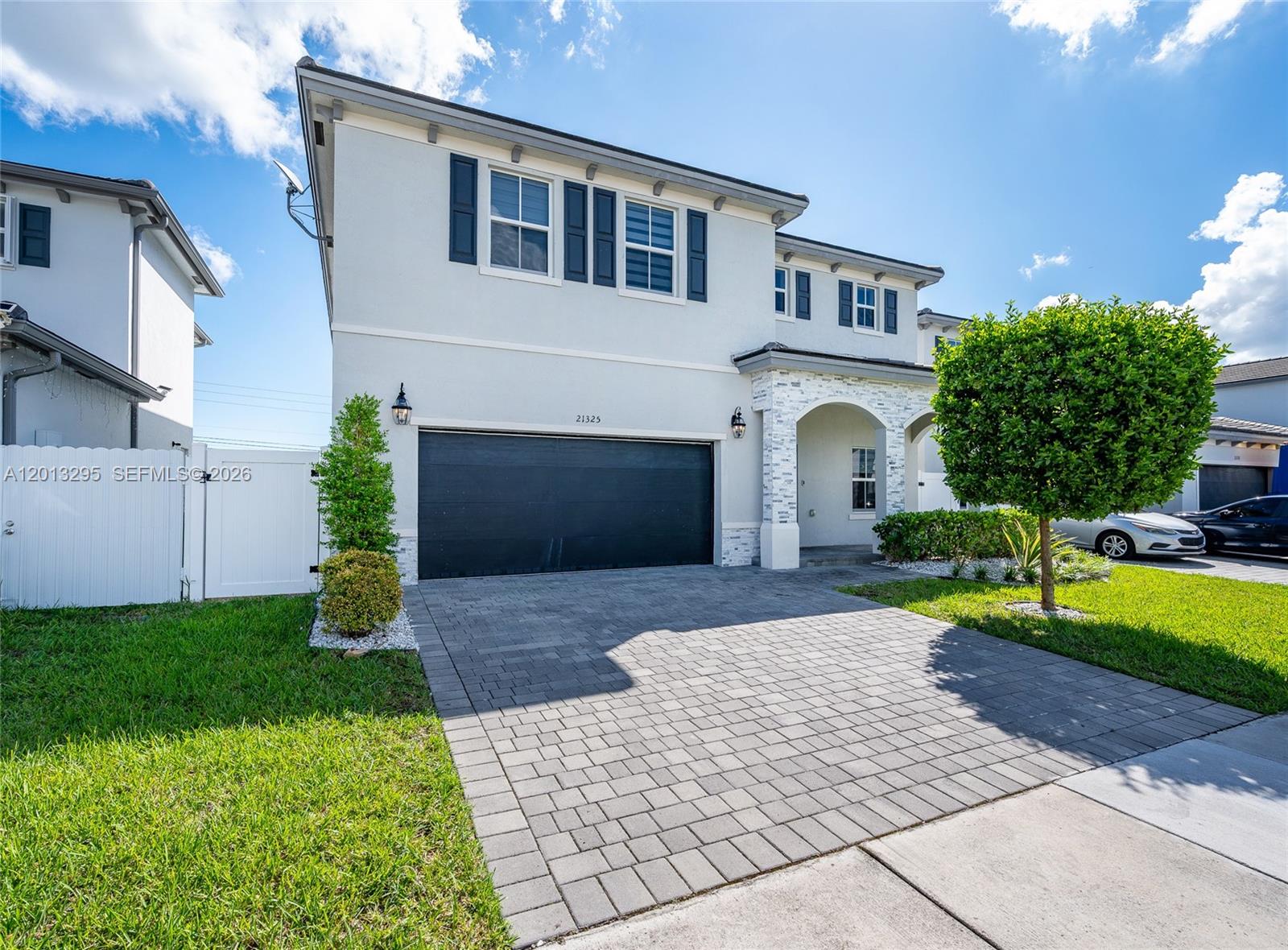 A two-story house features a paved driveway, a dark garage door, and stone accents — 21325 SW 127th Ct, Miami FL 33177, MIAMI, FL