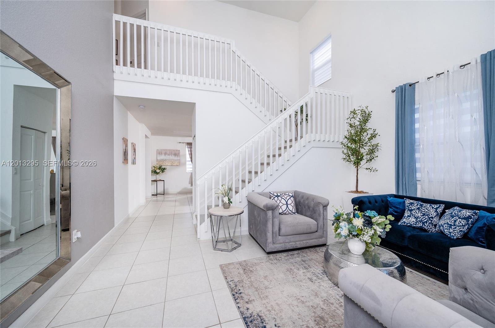 A living room features a staircase, white tile floors, a blue sofa, and gray armchairs — 21325 SW 127th Ct, Miami FL 33177, MIAMI, FL