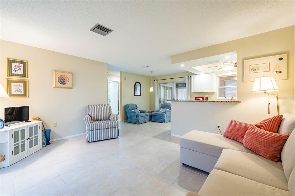 A living room with tile floors, a sectional sofa, and an open kitchen pass-through — 4479 MICHIGAN LANE, CLEARWATER, FL