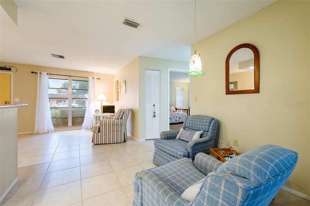 A living room with tile floors, two plaid armchairs, and a view of a bedroom — 4479 MICHIGAN LANE, CLEARWATER, FL