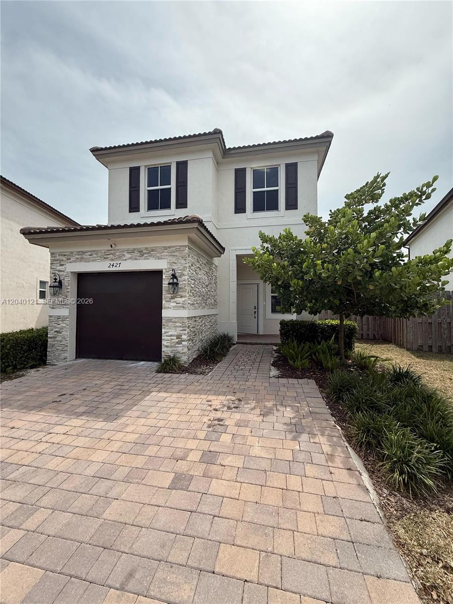 A two-story house features a stone-accented garage, a paved driveway, and a small front tree — 2427 NW 131st Cir, Miami FL 33167, MIAMI, FL
