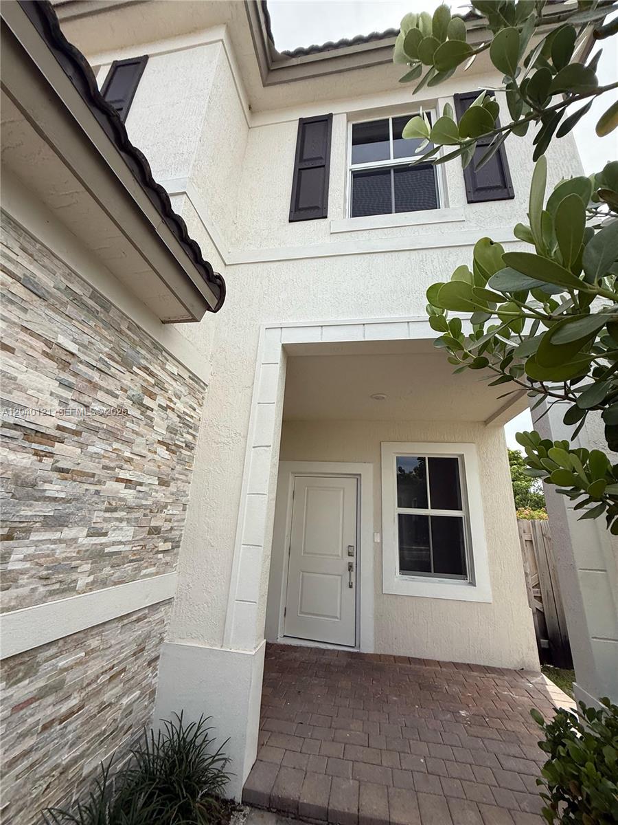 The exterior of a two-story house features a stone-veneer wall, a brick entryway, and shutters — 2427 NW 131st Cir, Miami FL 33167, MIAMI, FL