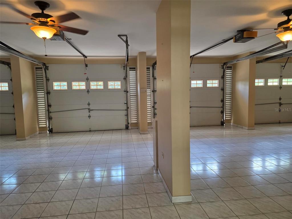 A spacious garage with tiled floors, multiple overhead doors, and ceiling fans — 17 DEL RECREO, CAGUAS, PR
