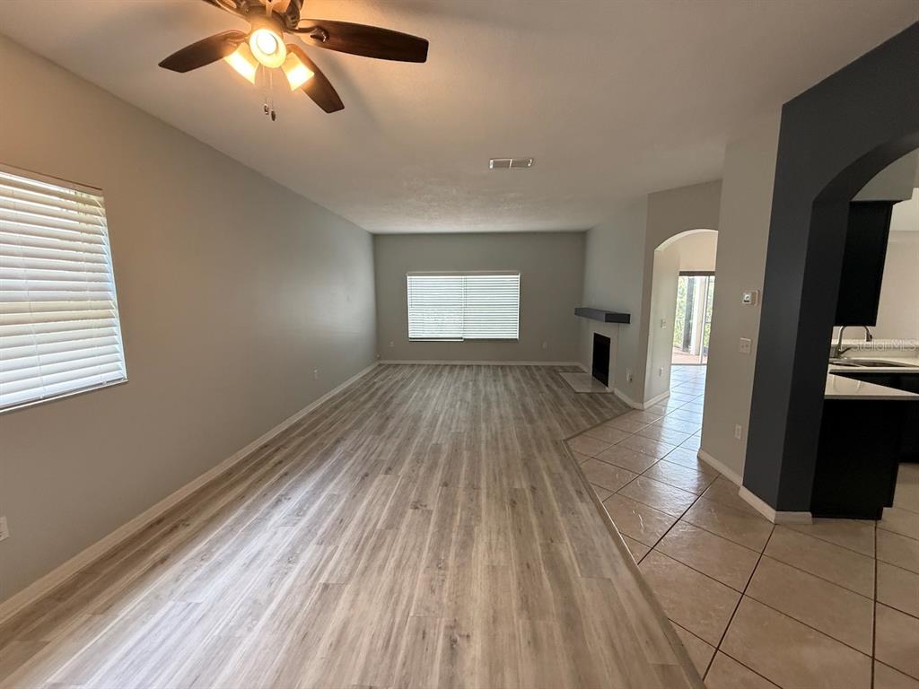 A living room features light wood-look flooring, a ceiling fan, and a fireplace — 162 HARWOOD CIRCLE, KISSIMMEE, FL