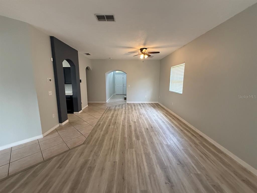 An interior view of a living room with wood-look flooring, tile entryway, and arched doorways — 162 HARWOOD CIRCLE, KISSIMMEE, FL