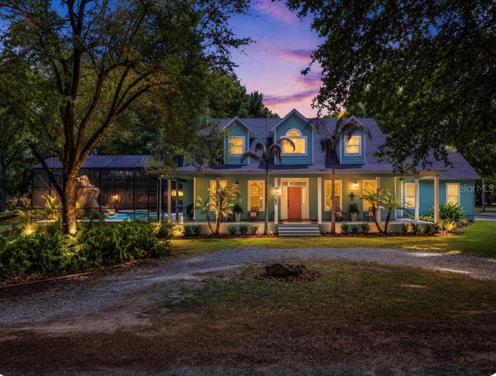 A light blue two-story house features a wrap-around porch and an attached two-car garage — 250 N WALKER STREET, OAKLAND, FL