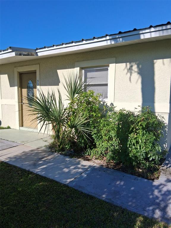 The exterior of a beige building features a front door, a window, and landscaping — 3311 ASH STREET, PUNTA GORDA, FL